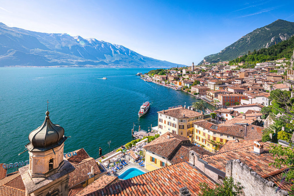 Uitzicht op Limone sul Garda aan het Gardameer, met kleurrijke huizen, bergen en een boot op het water.