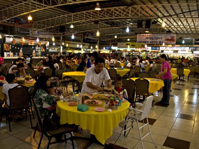 Drukke avondmarkt met eetkraampjes en gezinnen aan tafels in Kota Kinabalu, Maleisisch Borneo.