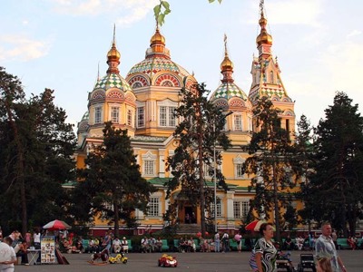 Russisch-orthodoxe kathedraal met kleurrijke koepels en torens, omringd door bomen en een plein.