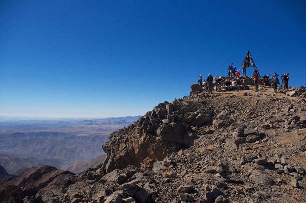 Wandelaars op de top van Mount Toubkal in Marokko, met uitzicht over het Atlasgebergte.