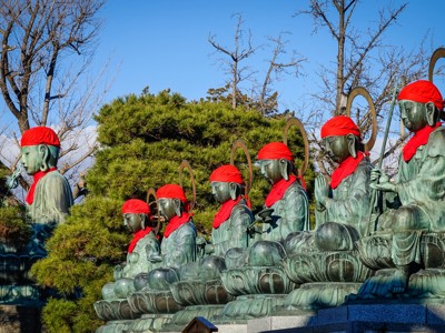 Jizo-beelden met rode mutsen en sjaals bij een Japanse tempel, Route Japan.