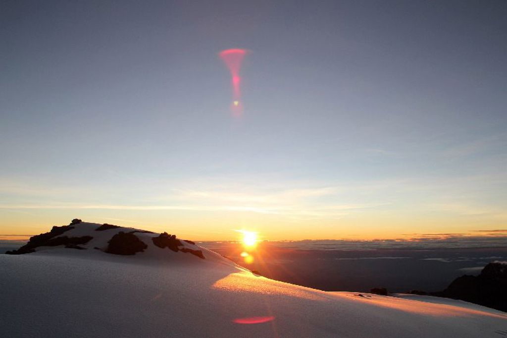 Zonsopkomst boven de besneeuwde top van de Kilimanjaro tijdens een wandelvakantie in Tanzania.