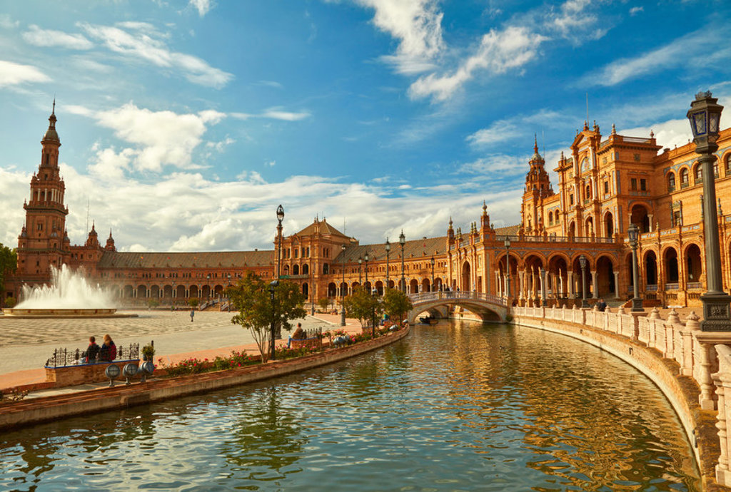 Plaza de España in Sevilla met fontein, kanaal en brug onder een blauwe lucht.