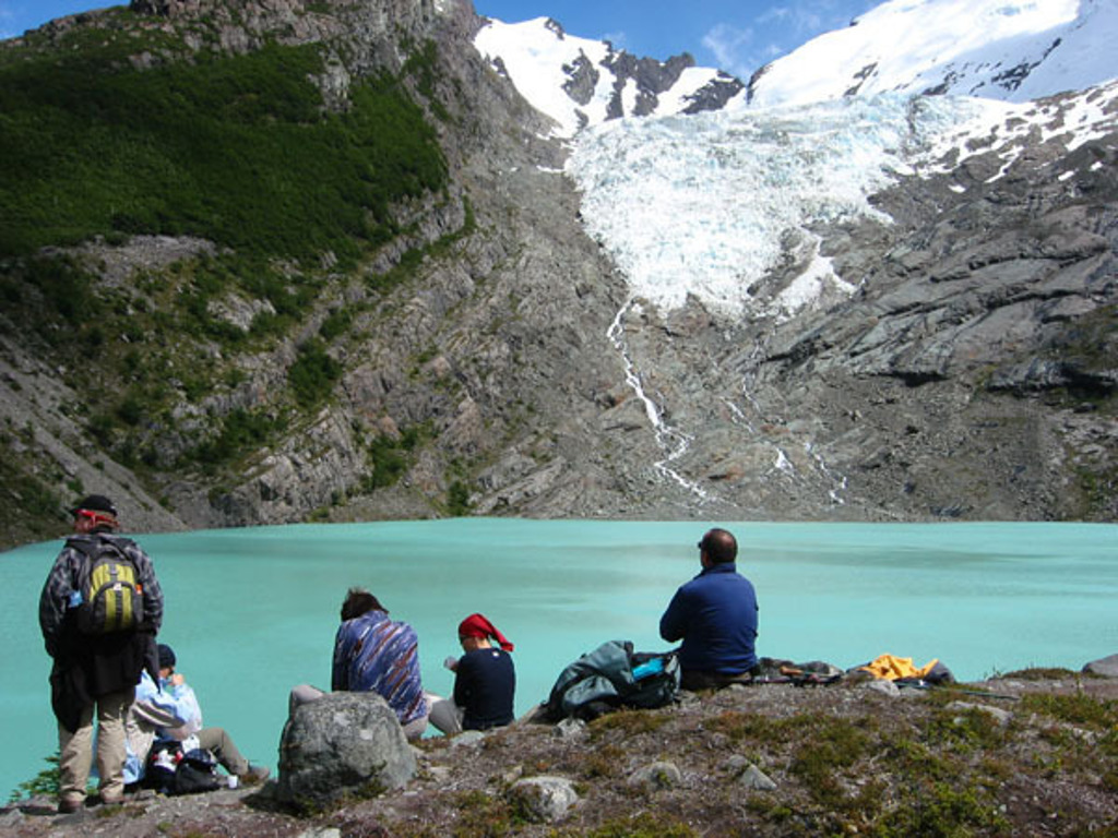 Groepsrondreis Argentinië: reizigers bij een turquoise gletsjermeer met besneeuwde bergen op de achtergrond.