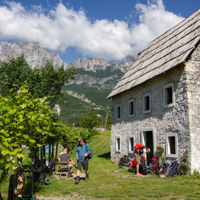 Wandelaars bij een berghut tijdens de wandelvakantie Peaks of the Balkan, met uitzicht op ruige bergtoppen.