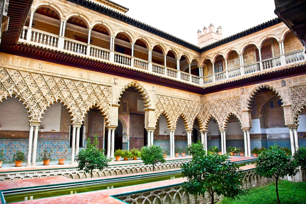 Binnenplaats van het Real Alcázar in Sevilla met Moorse bogen, tegelwerk en waterpartij in Andalusië.