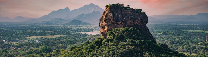 Sigiriya Leeuwenrots in Sri Lanka bij zonsondergang, met groen oerwoud en bergen op de achtergrond.