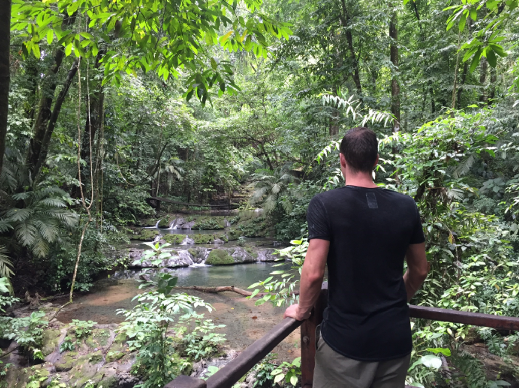 Reiziger kijkt uit over een waterval en rivier in de jungle tijdens een 22-35ers reis door Mexico.
