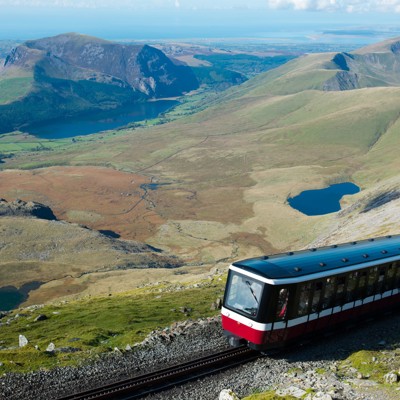 Trein van de Snowdon Mountain Railway met uitzicht over bergen en meren in Snowdonia, Wales.