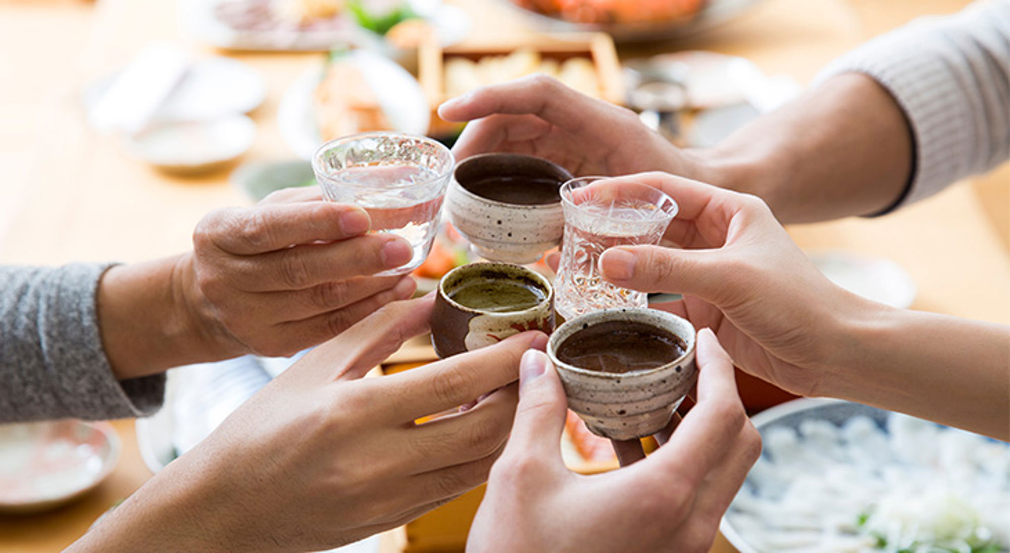 Sake drinken Proosten met sake tijdens een Japanse maaltijd.