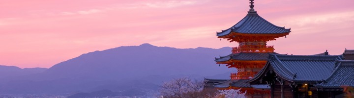 Kiyomizu-dera tempel in Kyoto bij zonsondergang, met kersenbloesem en uitzicht over de stad.