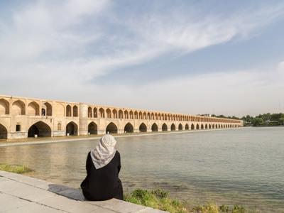Vrouw aan de rivier bij de Si-o-se-polbrug in Isfahan, Iran.