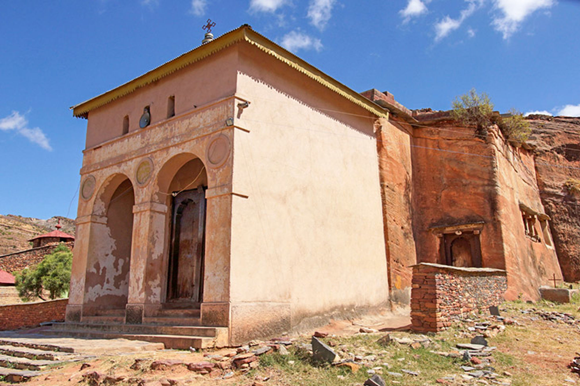 Orthodoxe kerk in Ethiopië Oude kerk uitgehouwen in rotswand met boogportaal onder blauwe lucht.