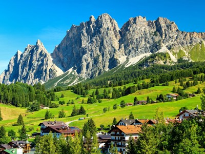 Groene alpenweiden en bergdorp met rotsmassief in de Dolomieten, Italië.