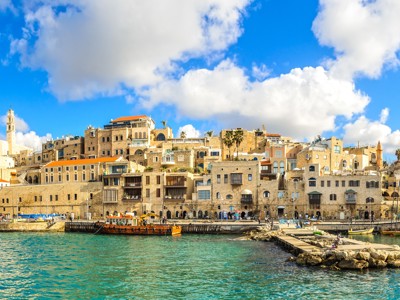 Panorama van de oude haven van Jaffa in Tel Aviv, met historische huizen aan zee onder een blauwe lucht.