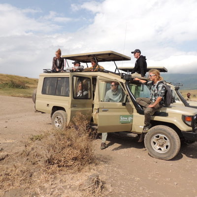 Safari-jeep met reizigers tijdens groepsrondreis Kenia en Tanzania, met uitzicht op savanne en bergen.