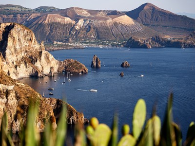 Uitzicht op de kust en vulkanische bergen van de Eolische Eilanden bij Sicilië, met zeilboten op zee.