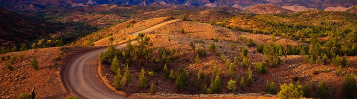Kronkelende onverharde weg door het berglandschap van de Flinders Ranges in Zuid-Australië bij zonsondergang.