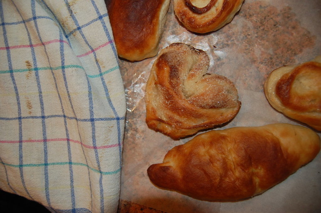Russische zoete broodjes en croissant op bakplaat naast een theedoek.