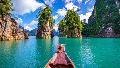 Longtailboot op het turquoise water van Khao Sok Nationaal Park in Thailand, met kalkstenen rotsen.