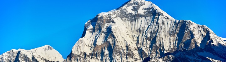 Besneeuwde top van de Dhaulagiri in Nepal tegen een helderblauwe lucht.