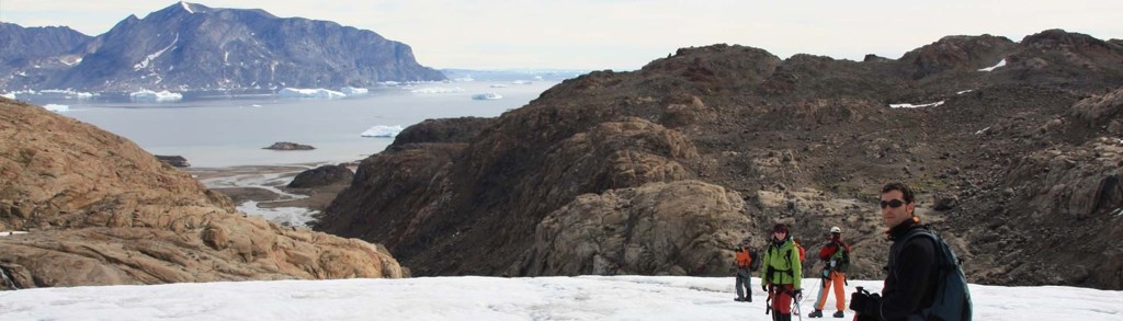 Wandelaars op een gletsjer met uitzicht op fjord en ijsbergen tijdens Groenland expeditie groepsrondreis.