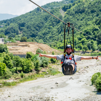 Man op zipline boven rivier in de bergen tijdens 22-35ers reis Albanië.