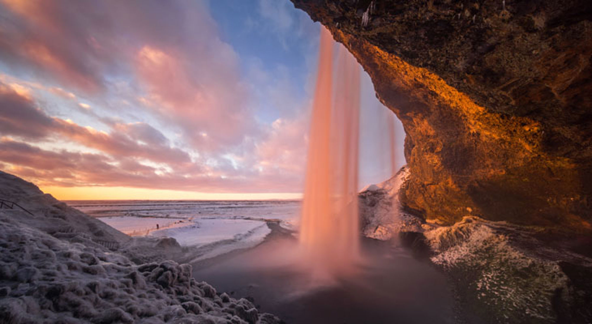 Seljalandsfoss IJsland Waterval Seljalandsfoss in IJsland bij zonsondergang, gezien vanaf achter de waterval.