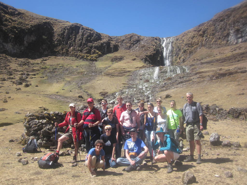 Groep wandelaars tijdens familiereis Peru bij een waterval in de Andes.