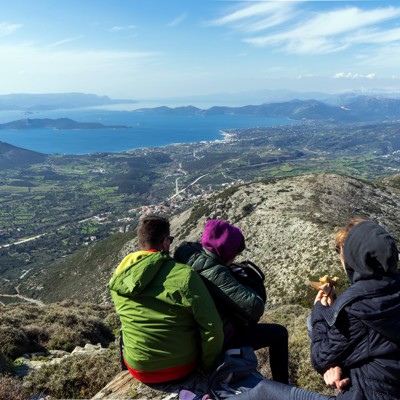 Wandelaars pauzeren op een bergtop op Evia met uitzicht op zee, eilanden en groene valleien in Griekenland.
