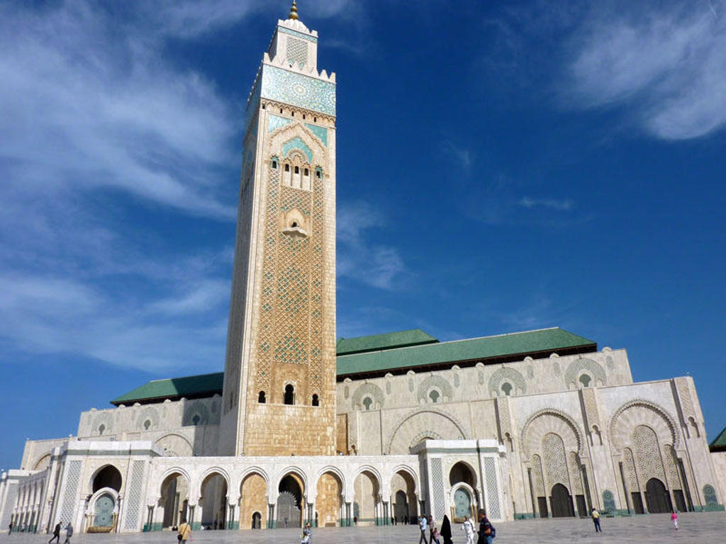 Hassan II-moskee in Casablanca, Marokko, met hoge minaret en witte bogen onder een blauwe lucht.