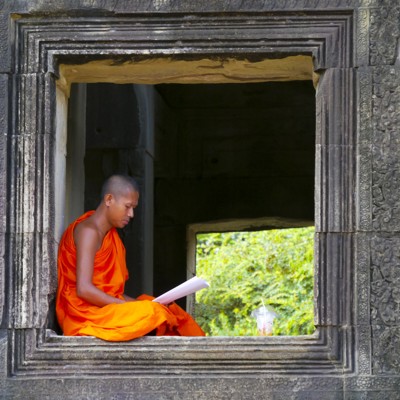 Boeddhistische monnik leest in een tempelraam tijdens fietsvakantie Vietnam, Cambodja en Thailand.