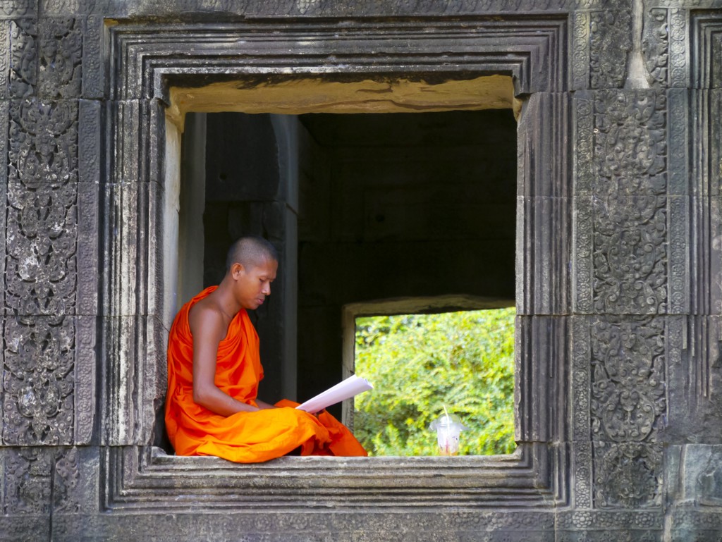 Boeddhistische monnik leest in een tempelraam tijdens fietsvakantie Vietnam, Cambodja en Thailand.