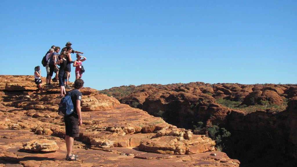 Groep wandelaars op rotsplateau met uitzicht over rood rotslandschap tijdens groepsrondreis Australië van Sydney naar Darwin.