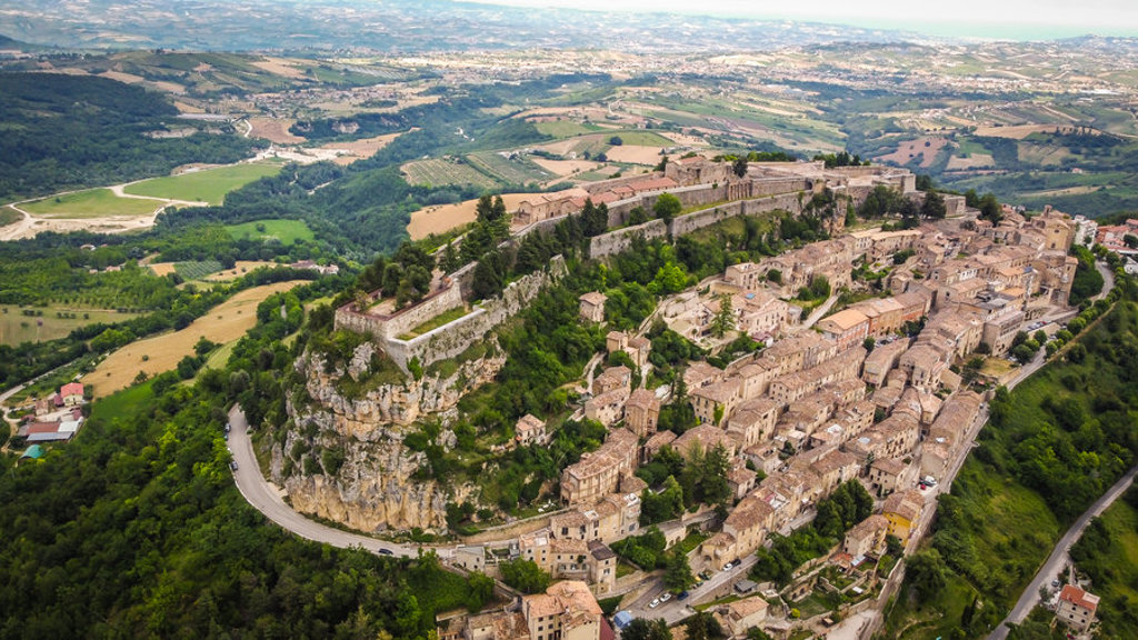 Middeleeuws bergdorp met fort op een rots, omringd door groene heuvels in de Centrale Apennijnen, Italië.
