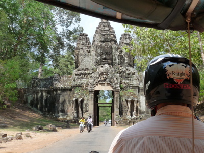 Tuk-tuk rijdt richting de Angkor Thom-poort met stenen gezichten bij Siem Reap, Cambodja.