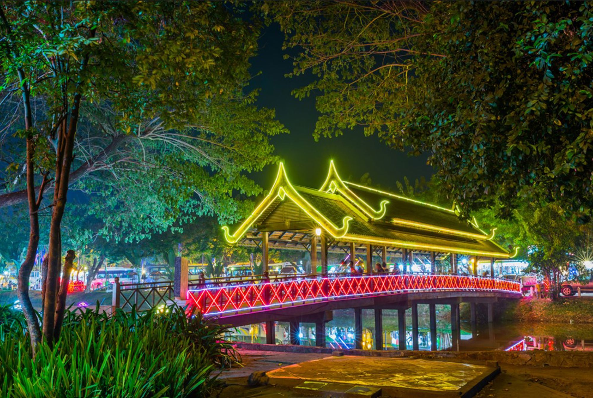 Verlichte brug met Khmer-paviljoen in een park bij nacht in Cambodja.