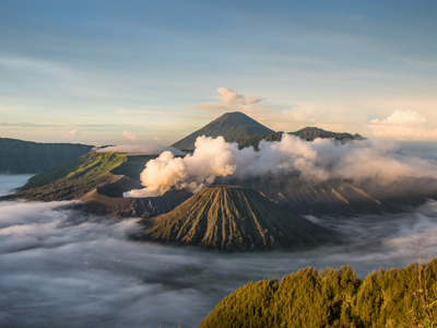 Vulkanlandschap op Java met rookpluimen en wolken boven de krater, tijdens familiereis Java & Bali.