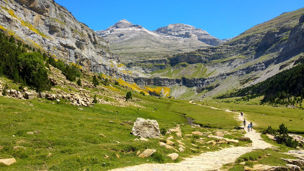 Wandelaars op bergpad door groene vallei in de Pyreneeën tijdens familiereis Spanje & Portugal.