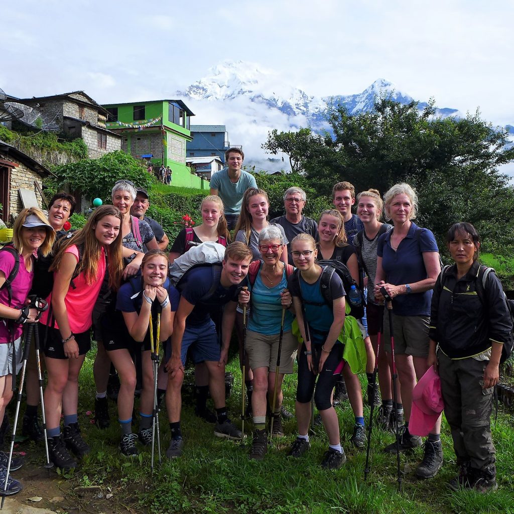 Groep wandelaars tijdens familiereis Nepal met besneeuwde Himalaya op de achtergrond.