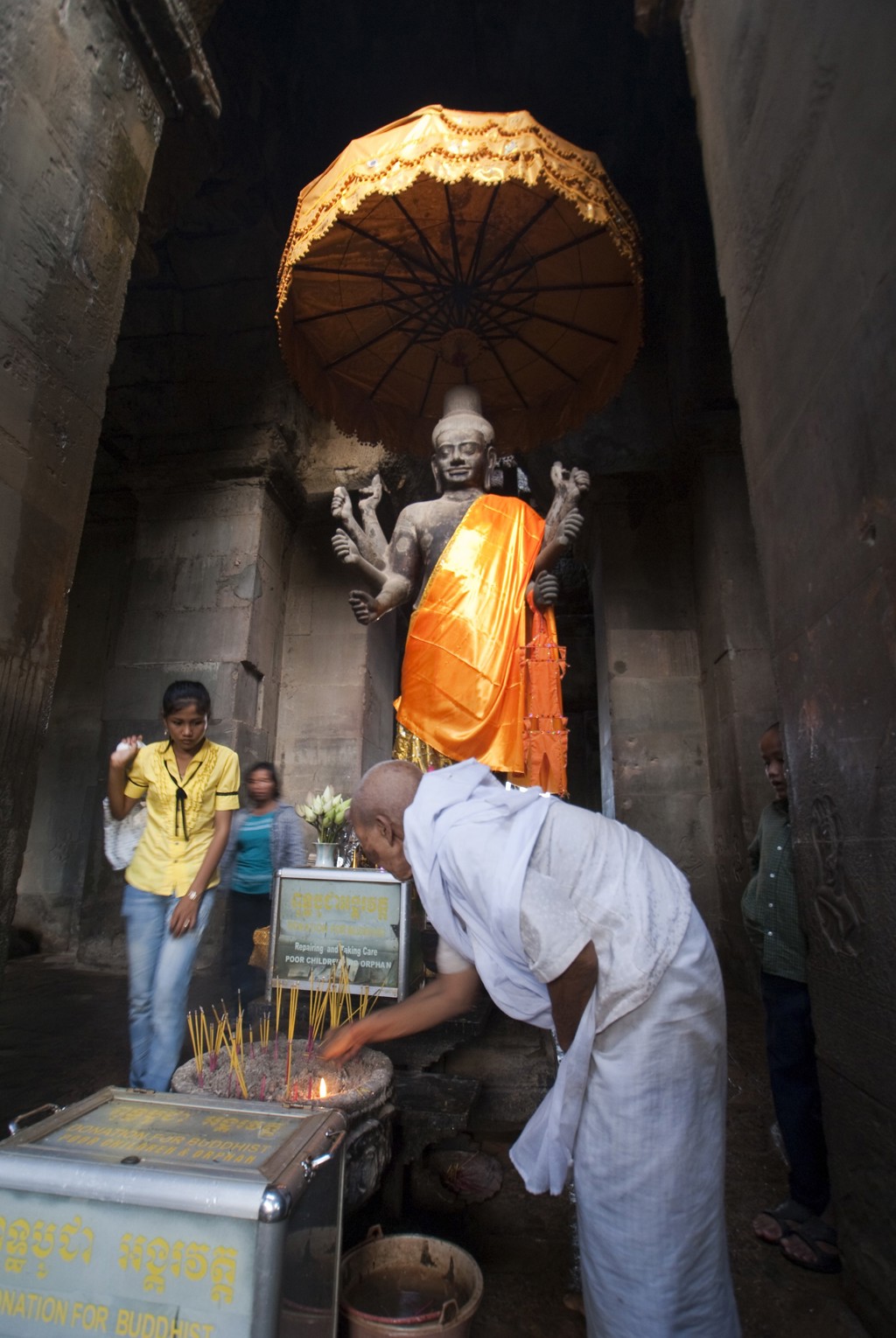 Monnik brandt wierook bij Boeddhabeeld in Angkor Wat, Cambodja.