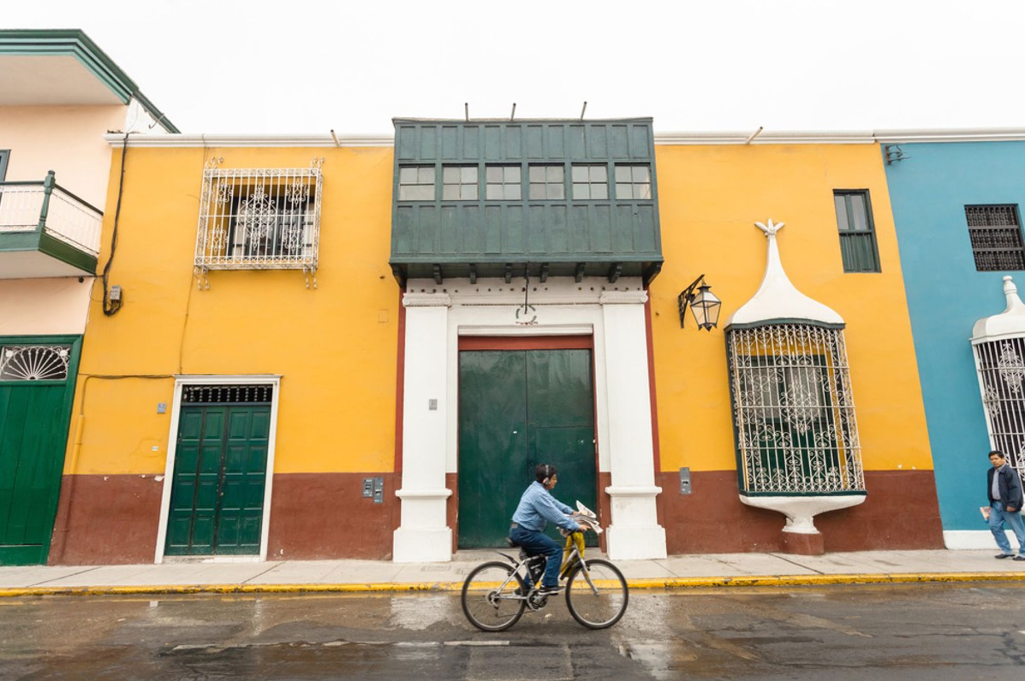 Kleurrijke gevels met balkons in Trujillo, Peru, met een fietser op straat.