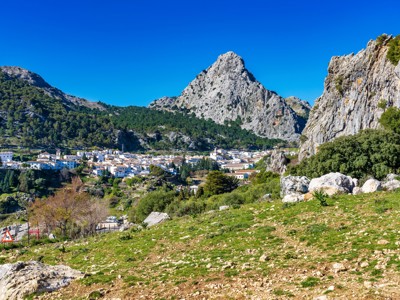 Wit Andalusisch bergdorp tussen rotswanden en groene heuvels in Spanje.