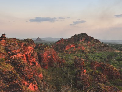 Rode rotsformaties en groene bush in de Kimberley-regio in West-Australië bij zonsondergang.