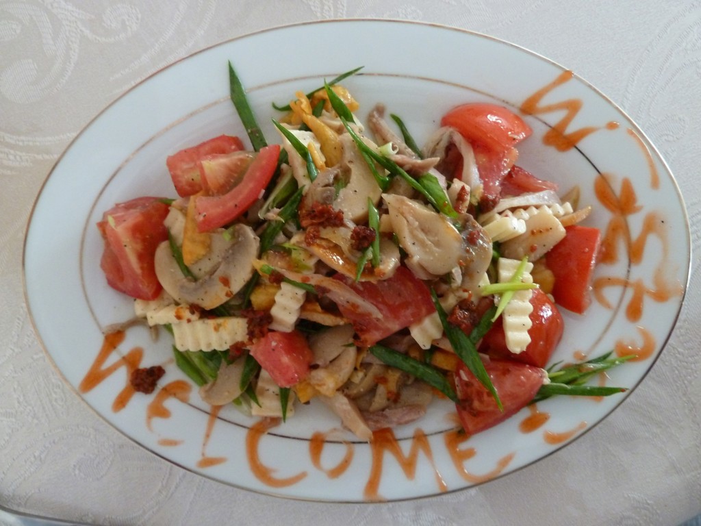 Bord met salade van tomaat, champignons en lente-ui tijdens de groepsrondreis Zijderoute.