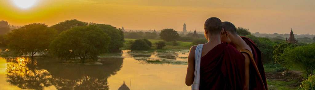 Monniken kijken uit over de tempels van Bagan bij zonsopgang, tijdens een groepsrondreis Myanmar.
