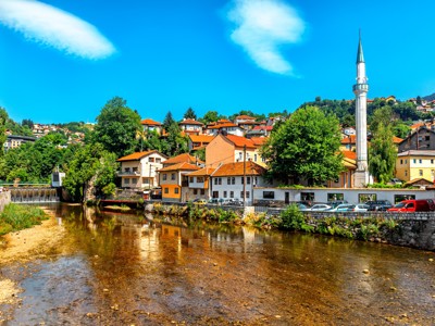 Uitzicht op Sarajevo met rivier, kleurrijke huizen en moskee-minaret in Bosnië en Herzegovina.