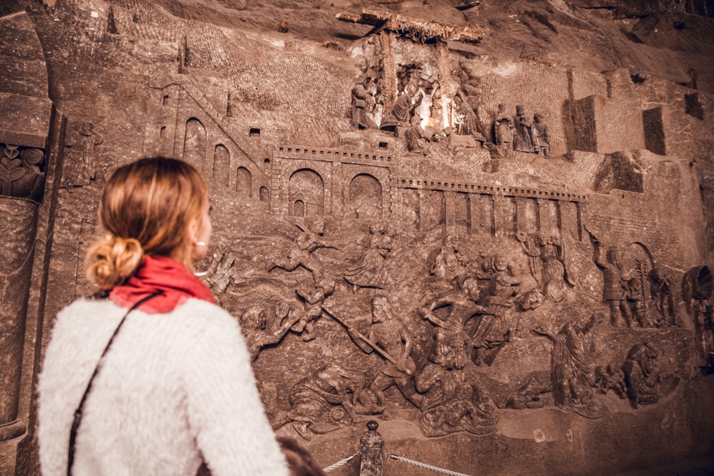 Reiziger bekijkt reliëfsculpturen in de Wieliczka-zoutmijn tijdens een groepsrondreis Polen.