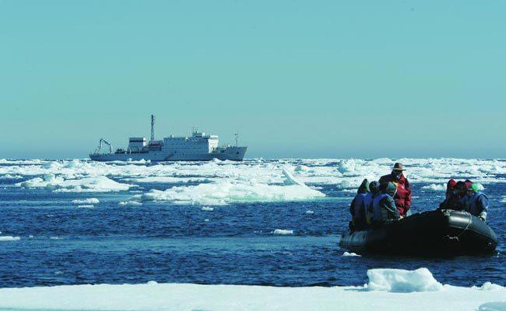 Cruiseschip vaart langs ijsbergen tijdens groepsrondreis van IJsland naar Groenland en Spitsbergen.