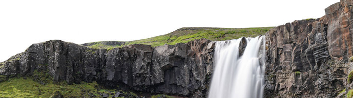Brede waterval die over een rotswand naar beneden stort in een groen berglandschap.